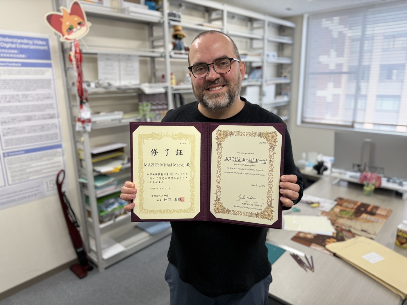 Michal Mazur holding his certificate for completing Ritsumeikan University's Practical Faculty Development Program for new faculty members.