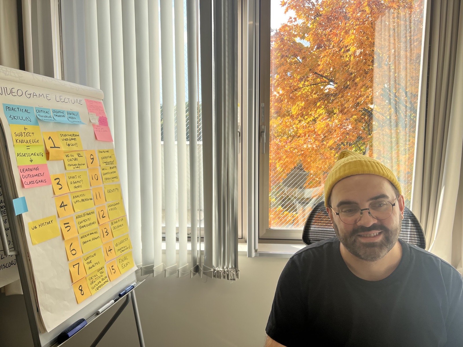 Michal Mazur beside a visual plan for a video games course.