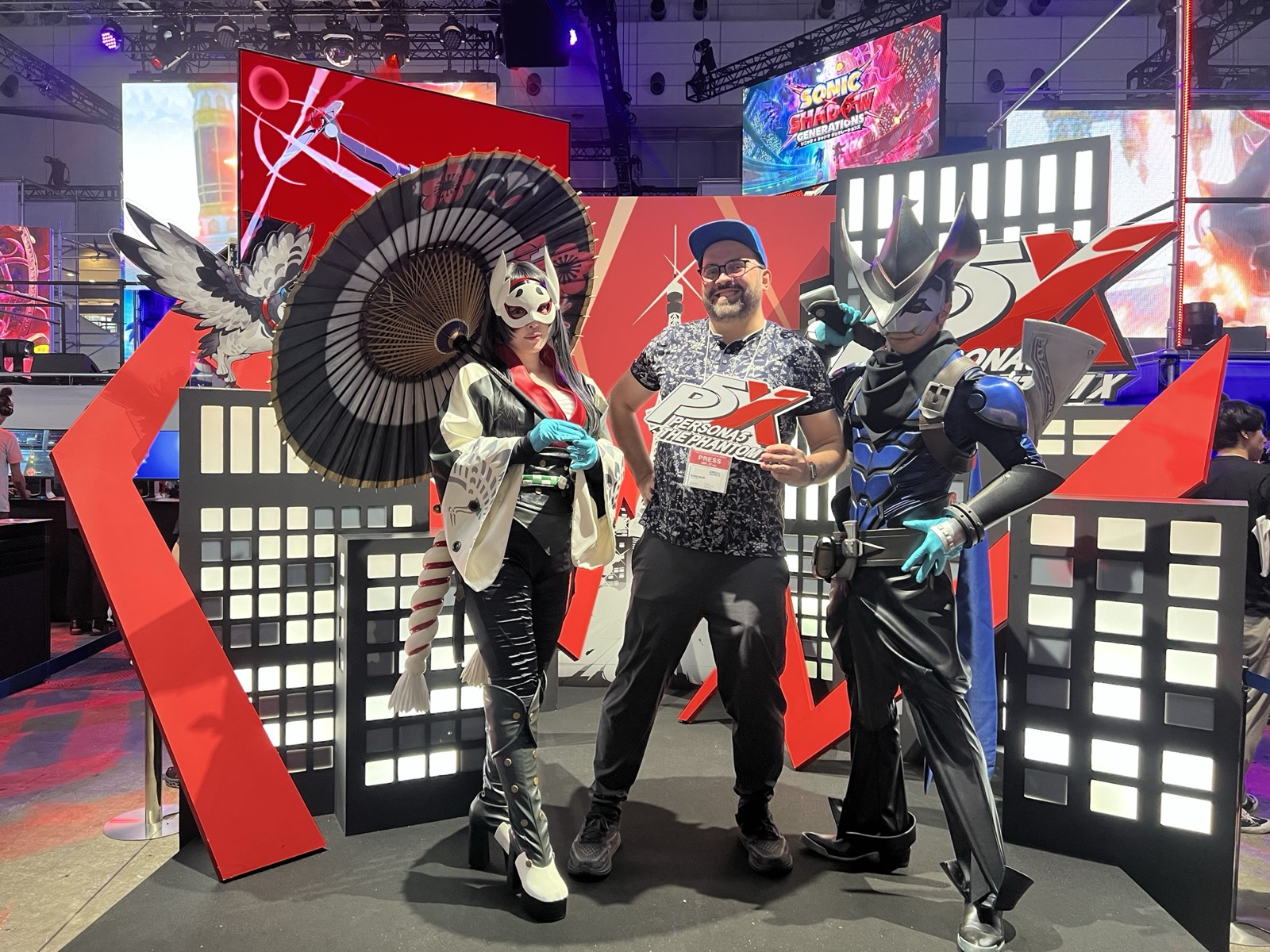 Michal Mazur at the Persona 5 booth at Tokyo Game Show, wearing a press badge.
